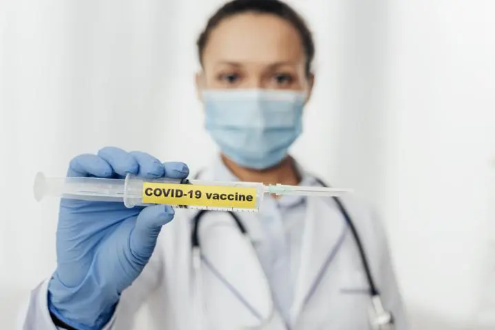 Doctor holding out the COVID-19 Vaccine